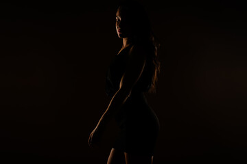 Fototapeta na wymiar Fit girl posing in black dress. Looking down