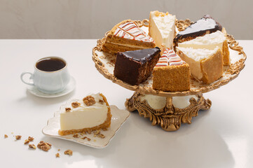 different pieces of cake on golden vintage plate on white table