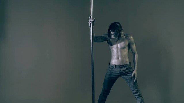 Pole dance. Sexy man dancing on pylon. Sexy slim and muscular male body. Flexible man gymnastic dancer man performing. Strong guy on pole dance. Shirtless gymnast exercising on pylon. Bare male torso.