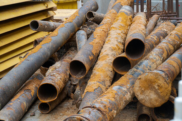 Pile of rusty old seweage pipes lying on construction site