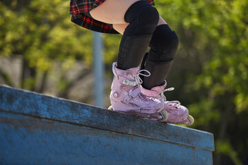Skater girl grinding on a ledge in a outdoor skatepark in summer. Aggressive inline roller blader female performing a bs royale grind trick