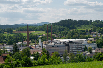 Fototapeta na wymiar The factory buildings of the Zwiesel Kristallglas AG in the town Zwiesel in Bavaria, Germany on sunny day with clouds