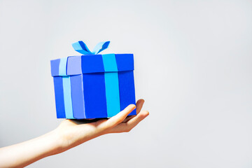 Blue gift box in hand on white background. Copy space for text, isolated. Celebration Birthday party concept