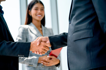 Close up two business man shake hands together in front of business woman with smiling and hold...