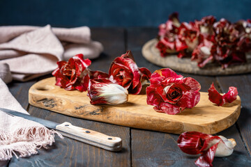 Kind of Red Radicchio or chicory - Rose of Gorizia on a wooden cutting board, knife, napkin over dark wooden surface - obrazy, fototapety, plakaty
