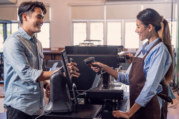 Female barita delivers cup of coffee to male customer and uses smartphone to pay with app, customer receives coffee for breakfast before going to work in coffee shop