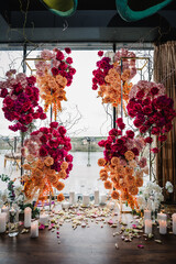 Wedding reception for luxury ceremony.  Photo-wall with view of pier, arch decorated pink, orange...