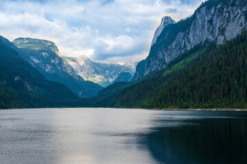 Beautiful landscape mountain forest lake view. Amazing summer cloudy scenery of Gosausee mountain lake and Dachstein mountain summit. Colorful scenery in Alps. Popular travel and hiking destination.