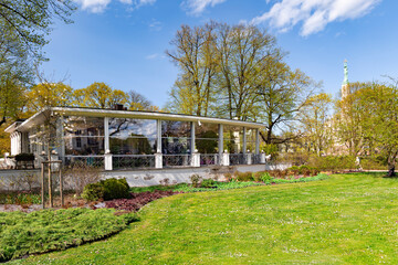 Obraz premium Beautiful spring trees and bushes of rhododendrons on the background Freedom Monument in Kronvalda Park, Riga, capital of Latvia.
