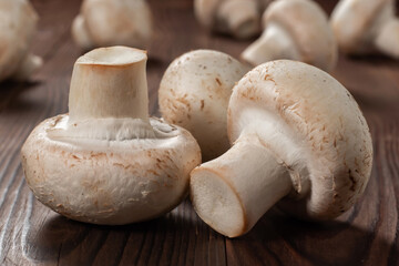 Fresh champignon mushrooms on wooden table, closeup.