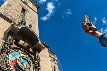 Unidentified person with a smartphone in the hand takes pictures of the astronomical clock in...
