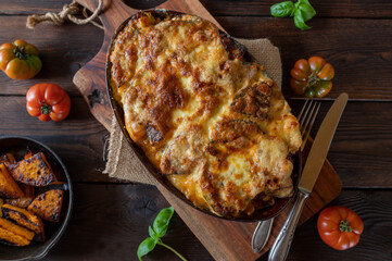 Lasagna with roasted pumpkin, cheese topping on rustic and wooden table