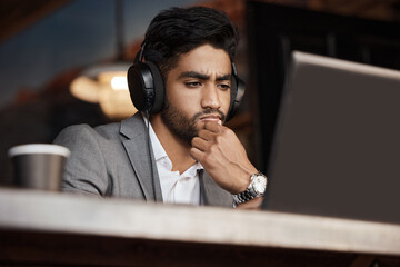 Fototapeta na wymiar Young business man, thinking and coffee shop with headphones, laptop or plan for schedule, report or analysis. Indian businessman, solution and ideas with brainstorming, web design and music in cafe