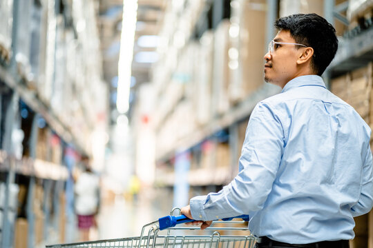 Businessmen enjoy using a trolley cart with looking to the shelves and finding goods in a large warehouse store. modern shopping lifestyle client furniture in hypermarkets.