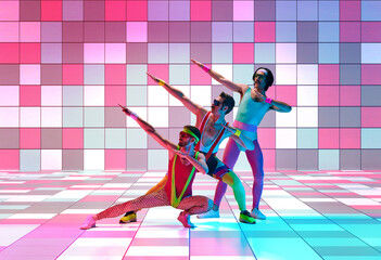 Young men in colorful, vintage sportswear training, doing exercises against multicolored mosaic studio background in neon light. Concept of sportive and active lifestyle, humor, retro style. Ad