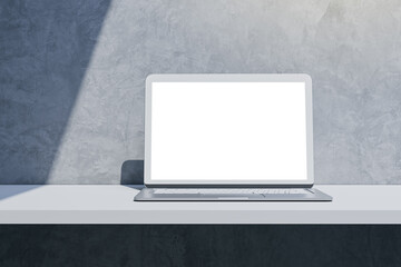 Close up of empty mock up laptop computer monitor on desktop and concrete wall background with shadow. Designer desktop and ad concept. 3D Rendering.