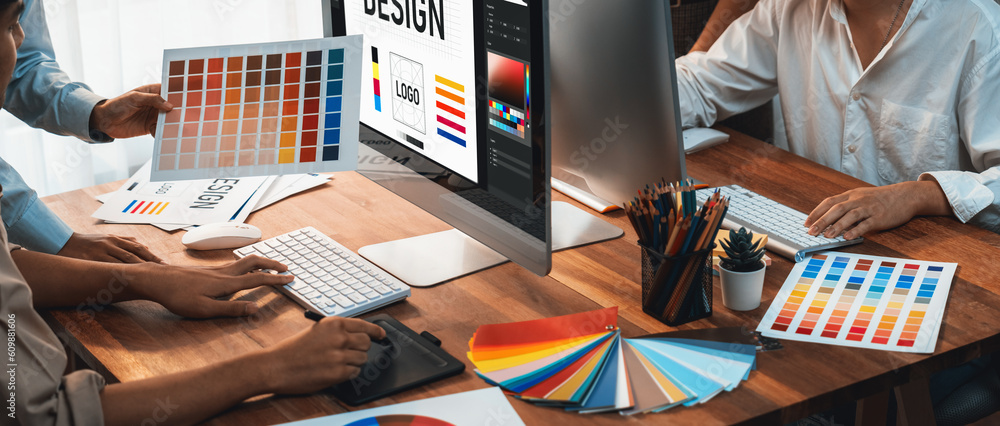Poster Graphic designer work on computer laptop and with graphic drawing pen while brainstorming unique design with professional graphic team in modern digital studio workplace. Panorama shot. Scrutinize