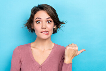 Fototapeta premium Closeup photo of funny lady direct thumb finger empty space commercial bite lips oops wear shirt isolated blue color background