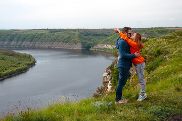 Fototapeta na wymiar Happy in love romantic cheerful couple man and woman hug and kiss. the summer mountains adventure enjoy the local nature. Copy space. Dniester river canyon, Subich, Ukraine