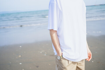 夏の海岸を歩くTシャツを着た男性