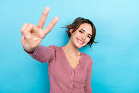 Photo of funny adorable lady showing v sign symbol on camera hey wear pink shirt outfit isolated blue color background
