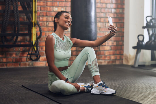 Gym, fitness or happy woman taking selfie on workout, exercise or training break for social media. Wellness, smile or healthy Indian girl smiling, relaxing or taking pictures for online post