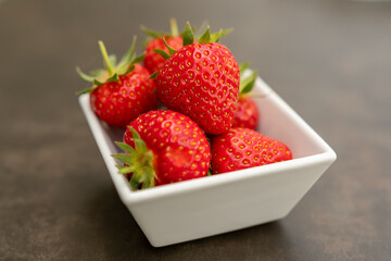 Erdbeeren in weisser Schale auf Tisch mit Textfreiraum