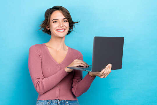 Portrait of nice cute good mood girl with short hairdo wear pink cardigan typing message on laptop isolated on blue color background