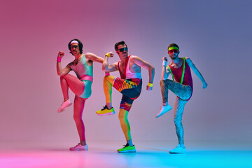 Sport show. Three funny men in colorful sportswear doing aerobics exercises against gradient blue...