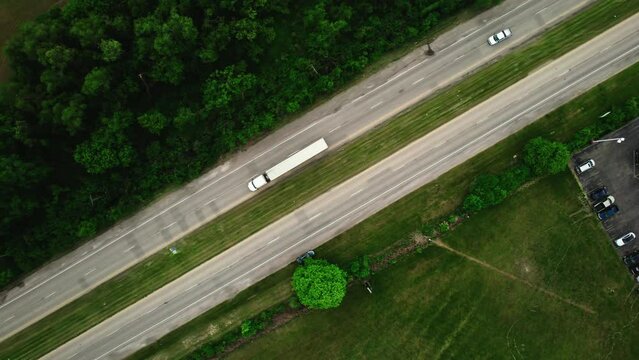 top down beautiful aerial of a dry van semi truck trailer entering a truck stop sorounded by green environment. Cinematic aerial, Wisconsin USA 4k