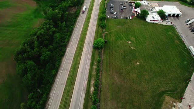 interesting aerial angle of a dry van semi truck trailer driving on a highway sorounded by green environment. Cinematic aerial, Wisconsin USA 4k