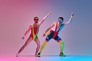 Young men, fitness coach in colorful sportswear stretching, training against gradient blue pink...