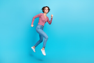 Fototapeta na wymiar Full length portrait of excited pretty person jumping rush empty space isolated on blue color background