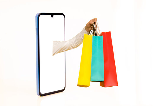 Hands with paper shopping bags outstreched from cellphone screen towards copy space, white background, isolated. Creative image for delivery service mobile application concept