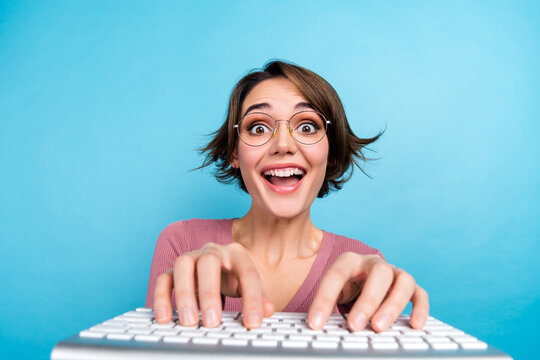 Portrait of ecstatic funny girl with short hairdo wear pink cardigan typing message in social media isolated on blue color background