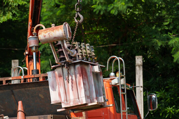 crane hook lifts up old distribution transformer