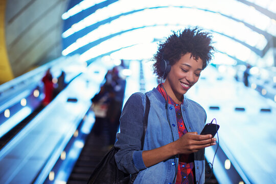 Smiling woman listening to mp3 player on escalator
