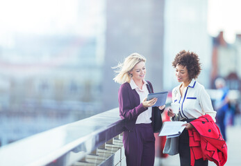 Businesswomen using digital tablet on urban bridge