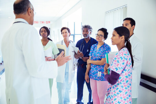 Doctor leading team meeting in hospital corridor