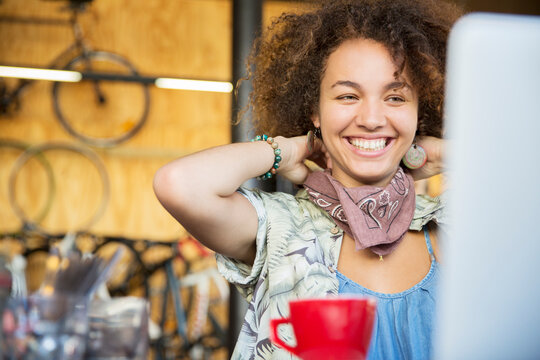 Smiling woman at laptop in bike shop adjusting neck scarf
