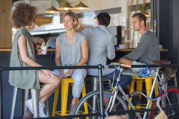 Friends hanging out talking and drinking coffee on cafe patio