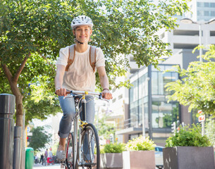 Portrait smiling young woman in helmet riding bicycle in urban park