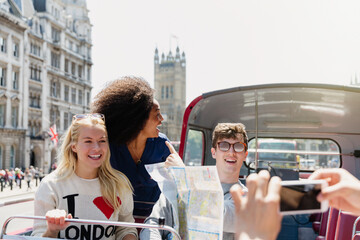 Friends with map riding double-decker bus, London, United Kingdom