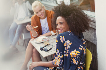 Portrait smiling woman with friend at sidewalk cafe