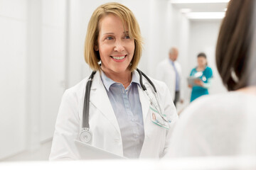 Smiling doctor talking to patient in hospital corridor