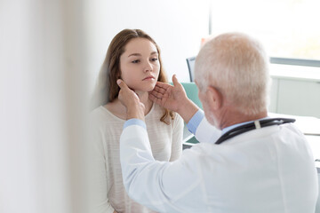 Doctor checking teenage patient‚Äôs glands in examination room