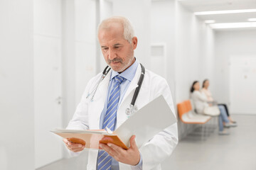 Doctor making rounds reviewing medical record in hospital corridor