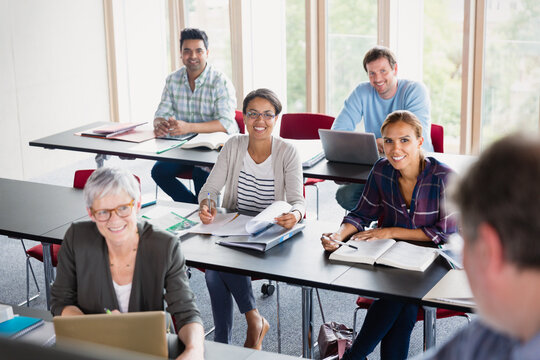 Smiling students watching teacher in adult education classroom