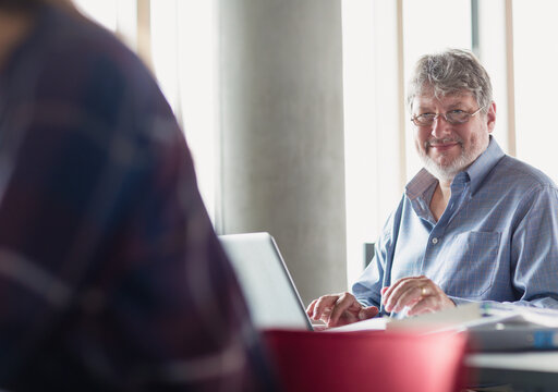 Portrait smiling man working at laptop in adult education classroom