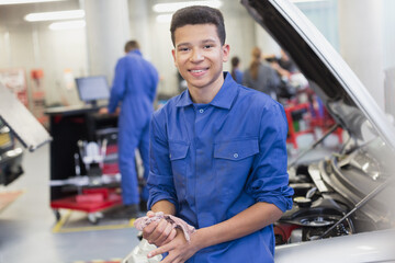 Portrait smiling mechanic leaning on car in auto repair shop - obrazy, fototapety, plakaty